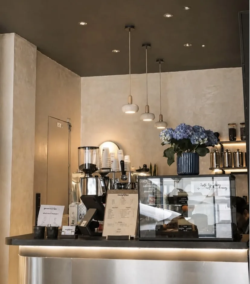 Le comptoir : machine espresso, vitrine de pâtisseries, hortensias bleus